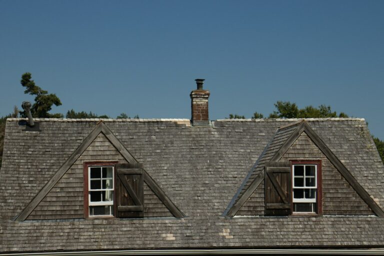 A homeowner examines damaged shingles and metal flashing near a roof edge while checking for signs of water intrusion.